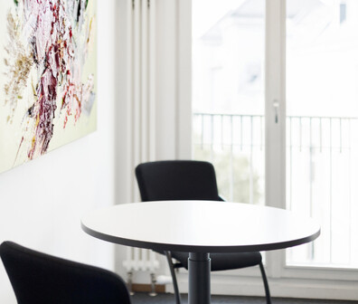 Ein weißer runder Tisch mit zwei schwarzen Stühlen