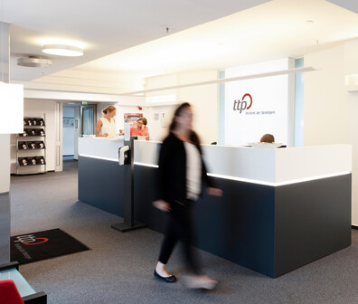 Eine Frau im Anzug geht durch ein ttp Büro