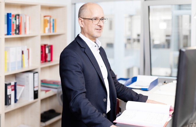 Thomas Bertram steht am Schreibtisch