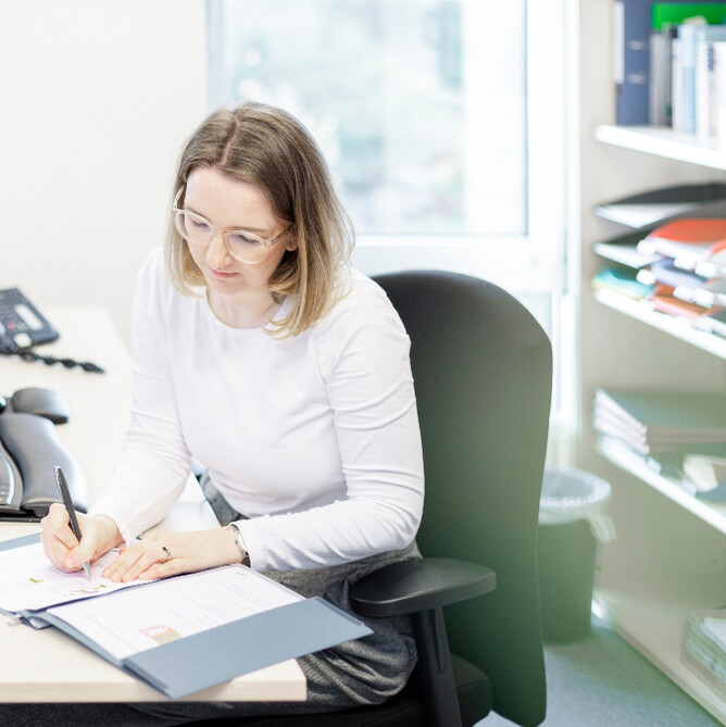 Eine ttplerin im weißen Shirt unterschreibt ein Dokument