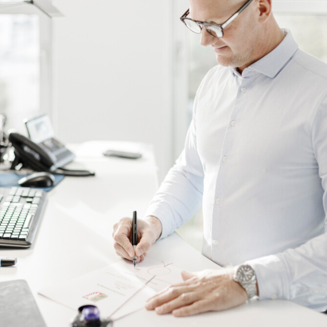 Ein ttpler mit Brille unterschreibt ein Dokument