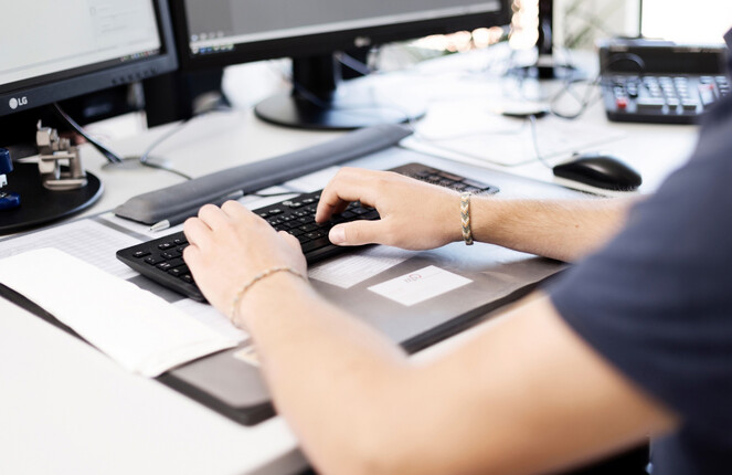 Rechteckiges Bild von einem Mann der am Computer tippt