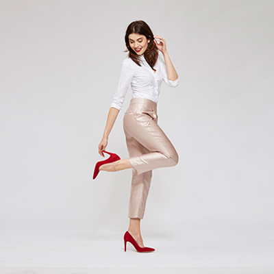 Eine Frau posiert stehend vor einem grauen Hintergrund. 